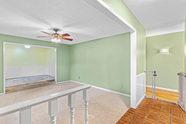 hallway with a textured ceiling, carpet floors, baseboards, and tile patterned floors