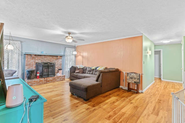living room with wood finished floors, ceiling fan, a textured ceiling, a fireplace, and plenty of natural light