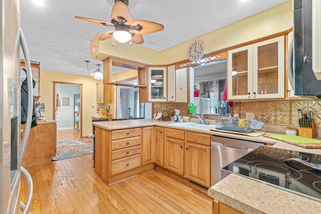 kitchen with stainless steel appliances, a sink, light wood-type flooring, ceiling fan, and decorative backsplash