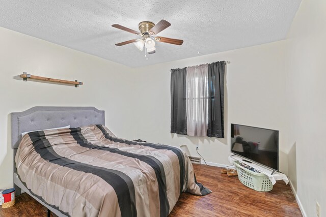 bedroom with wood finished floors, baseboards, a textured ceiling, and ceiling fan