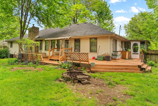 rear view of house with an outdoor fire pit, a sunroom, a chimney, a wooden deck, and central AC unit