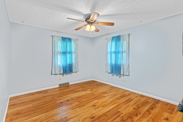 spare room featuring light wood-type flooring, ceiling fan, a textured ceiling, and baseboards