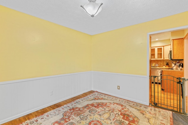 unfurnished room featuring wainscoting and wood finished floors