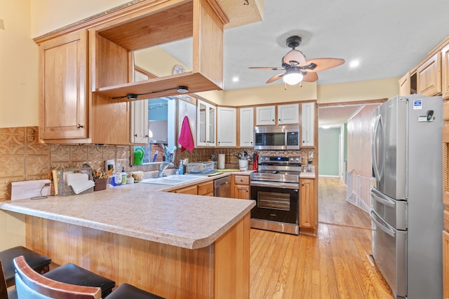 kitchen featuring stainless steel appliances, light countertops, a peninsula, and a sink