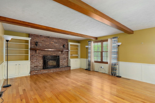 4855 E Cimarron Ln, Springfield, MO 65803 - unfurnished living room featuring beam ceiling, wood finished floors, a textured ceiling, a wainscoted wall, and built in features