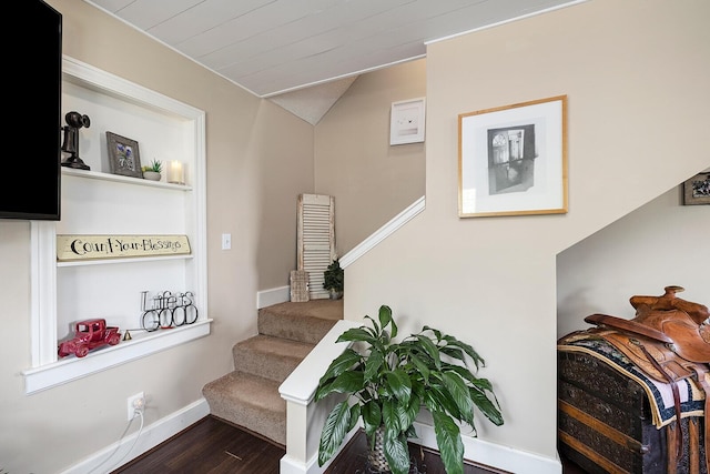 stairway with wood finished floors, lofted ceiling, and baseboards