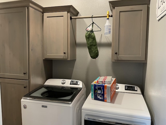laundry area with independent washer and dryer, a textured wall, and cabinet space