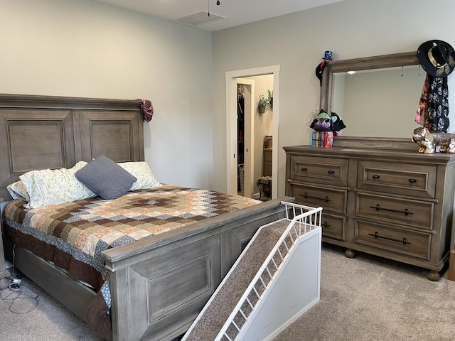 bedroom with light colored carpet, a walk in closet, and a closet