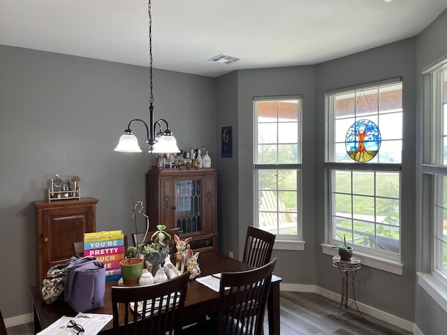 dining space featuring wood finished floors, a chandelier, healthy amount of natural light, and baseboards