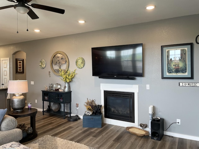 living room featuring wood finished floors, a ceiling fan, a glass covered fireplace, recessed lighting, and baseboards