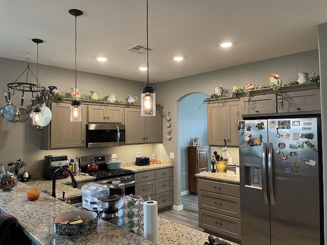 kitchen featuring appliances with stainless steel finishes, light stone countertops, light wood finished floors, pendant lighting, and recessed lighting