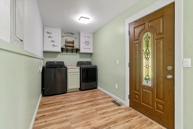 79 County Road 101, Gainesville, MO 65655 - laundry area featuring light wood-style flooring, cabinet space, baseboards, a textured ceiling, and washing machine and dryer