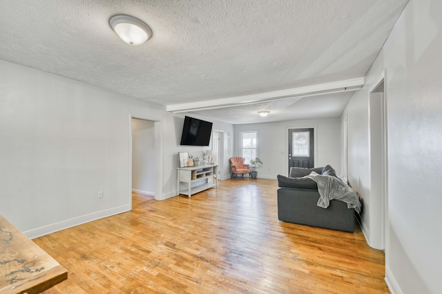 living area featuring a textured ceiling, light wood-style flooring, and baseboards