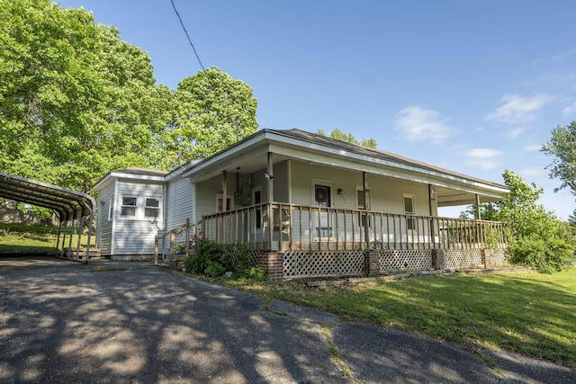 view of front facade featuring covered porch, asphalt driveway, a front yard, and a carport
