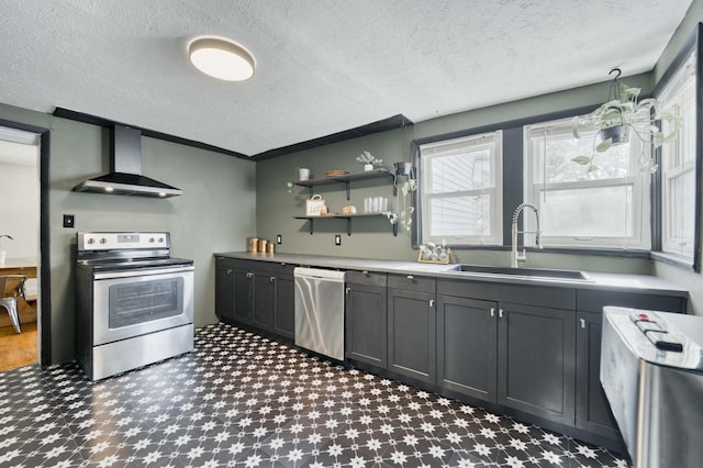 kitchen with appliances with stainless steel finishes, wall chimney exhaust hood, a sink, plenty of natural light, and a textured ceiling