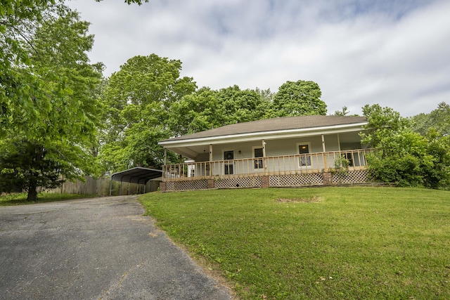 farmhouse inspired home featuring a porch, a front yard, asphalt driveway, and a carport