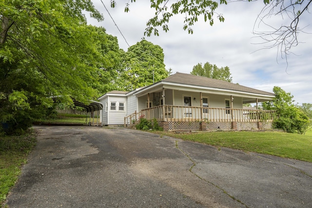 view of front of home with a carport, a porch, driveway, and a front yard