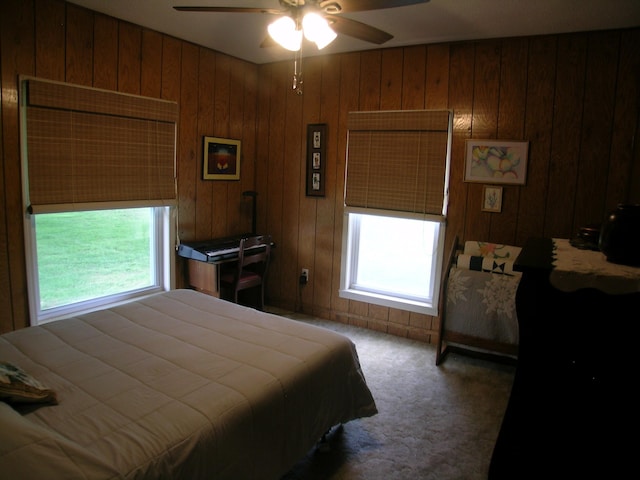 bedroom featuring carpet floors, wooden walls, and a ceiling fan