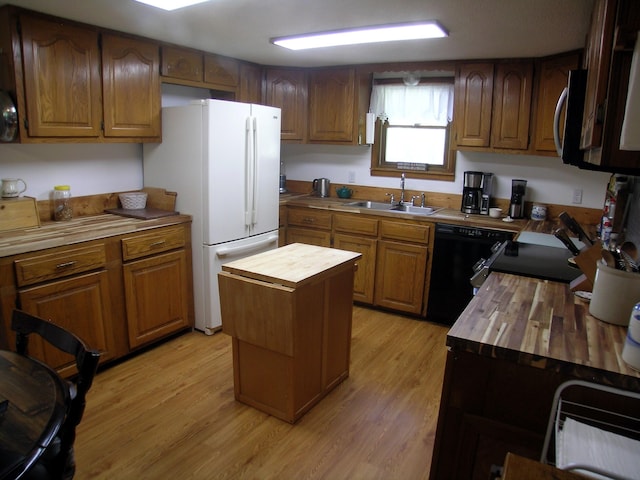 kitchen featuring wood counters, a sink, freestanding refrigerator, and light wood-style floors