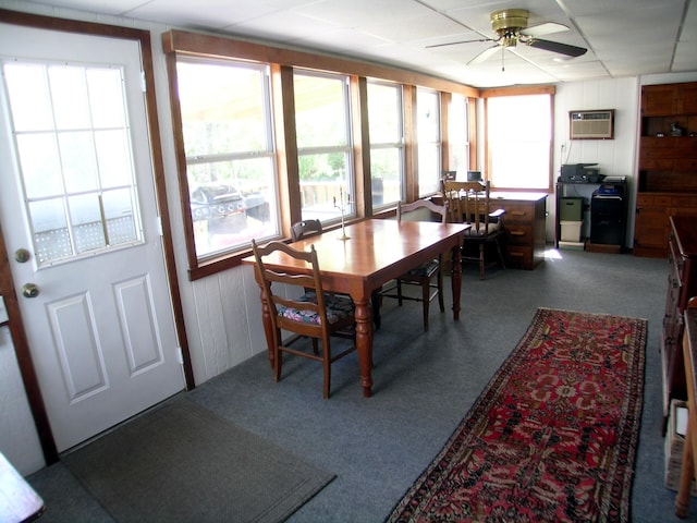 dining area featuring healthy amount of natural light, a ceiling fan, an AC wall unit, carpet flooring, and wooden walls