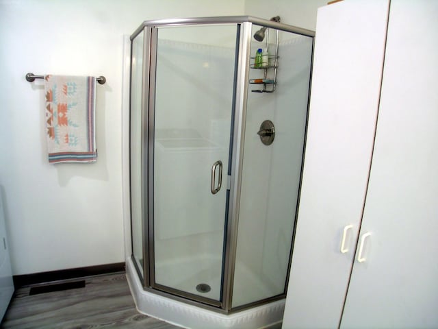 full bath with a shower stall, wood finished floors, and baseboards