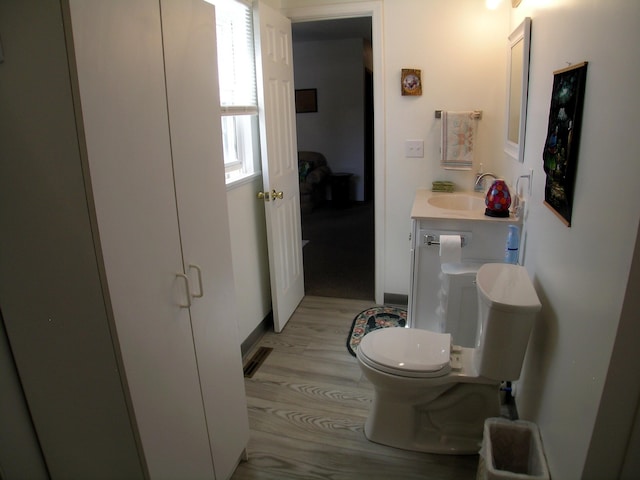half bath featuring a sink, wood finished floors, toilet, and baseboards