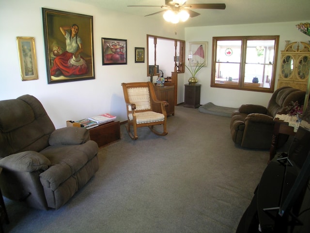 carpeted living area with a ceiling fan