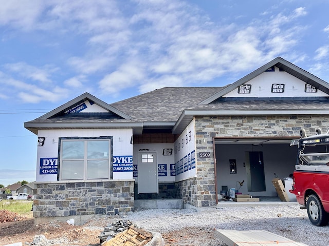 property in mid-construction featuring stone siding, a garage, and roof with shingles