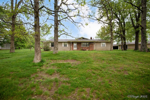 rear view of property featuring brick siding, a lawn, and a chimney