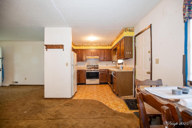 kitchen with white appliances, under cabinet range hood, light countertops, brown cabinets, and light carpet