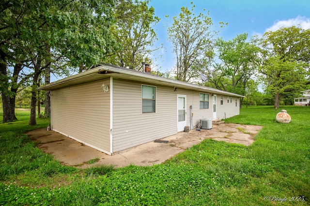 rear view of property featuring a yard, central AC unit, and a chimney