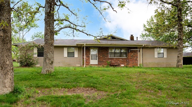 view of front of home with a chimney, a front lawn, and brick siding