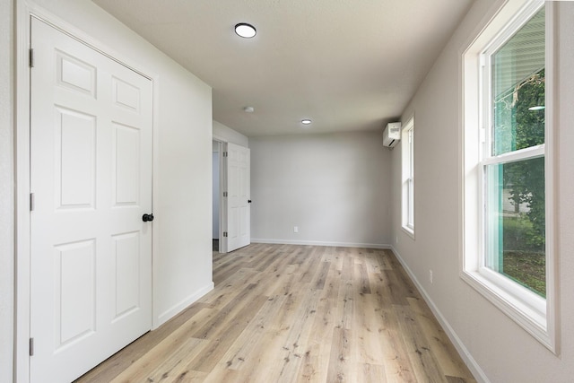 spare room with light wood-style flooring, baseboards, recessed lighting, and a wall mounted AC