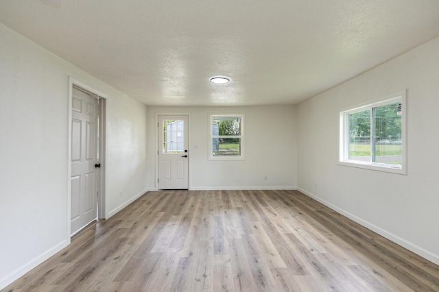 entrance foyer with light wood-style flooring, baseboards, and a textured ceiling