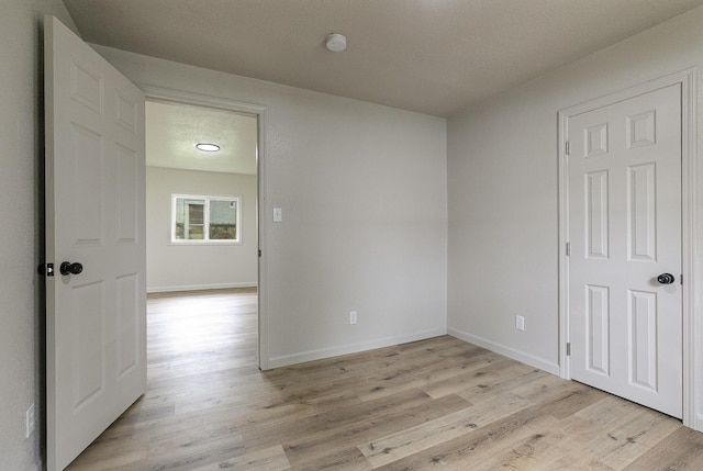 unfurnished room with light wood finished floors, baseboards, and a smoke detector