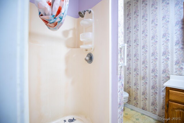 bathroom with a shower, vanity, tile patterned floors, and baseboards
