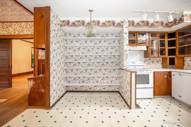 kitchen with white appliances, under cabinet range hood, wallpapered walls, light countertops, and light flooring