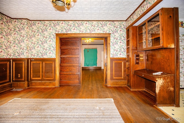 dining room with wallpapered walls, hardwood / wood-style flooring, wainscoting, and an ornate ceiling