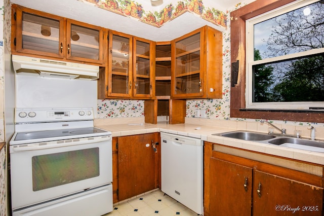 kitchen featuring white appliances, under cabinet range hood, brown cabinets, and light countertops
