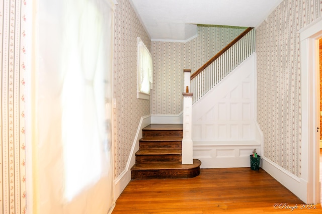 staircase with hardwood / wood-style floors and wallpapered walls