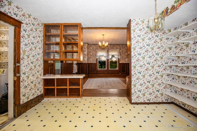 interior space featuring wallpapered walls, a chandelier, baseboards, and tile patterned floors