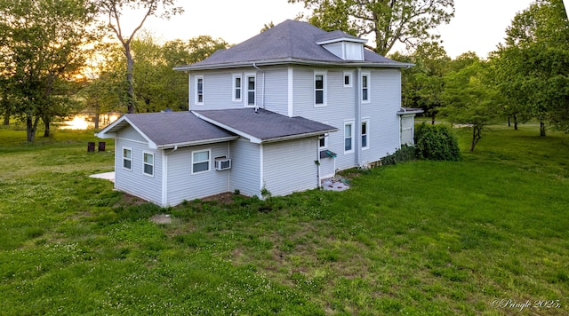 rear view of property featuring a lawn, roof with shingles, and cooling unit