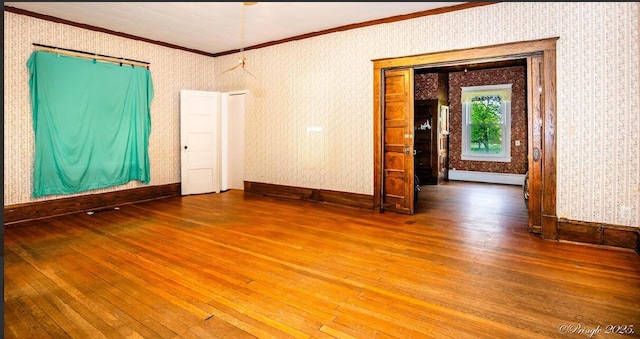 unfurnished room featuring ornamental molding, wood-type flooring, baseboards, and wallpapered walls