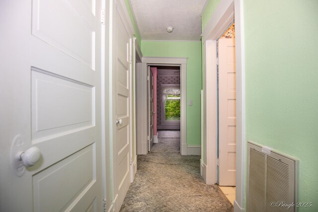 corridor featuring a textured ceiling and light colored carpet