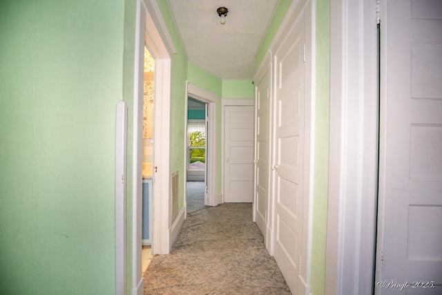hall featuring light carpet and baseboards