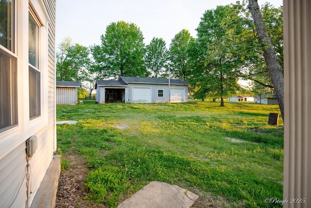 view of green lawn featuring a detached garage and an outbuilding