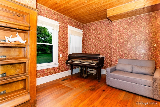 sitting room with wallpapered walls, hardwood / wood-style flooring, ornamental molding, wooden ceiling, and baseboards