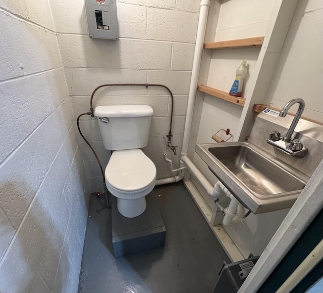 908 N Lincoln, Neosho, MO 64850 - half bathroom featuring toilet, finished concrete flooring, concrete block wall, and a sink