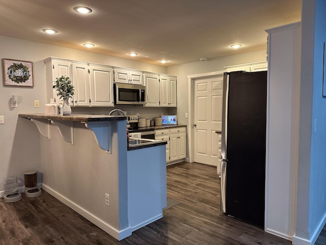 313 Washington St, Mountain View, MO 65548 - kitchen with appliances with stainless steel finishes, a peninsula, dark countertops, dark wood-style flooring, and recessed lighting