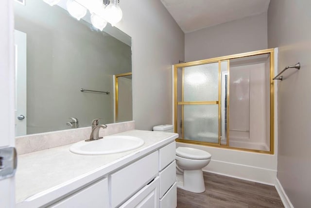 bathroom with vanity, wood finished floors, toilet, and combined bath / shower with glass door